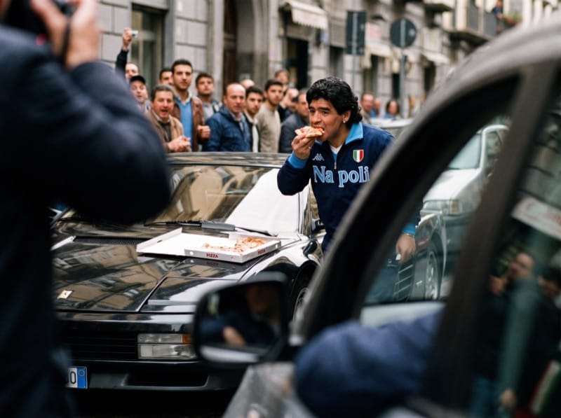 Diego con la camiseta del Napoli entre la gente, visto desde un auto